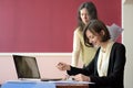 Young smartly dressed lady helps another young lady to work with documents, fill forms and sign Royalty Free Stock Photo