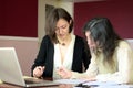 Young smartly dressed lady helps another young lady to work with documents, fill forms and sign Royalty Free Stock Photo