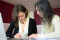 Young smartly dressed lady helps another young lady to work with documents, fill forms and sign Royalty Free Stock Photo