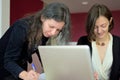 Young smartly dressed lady helps another young lady to work with documents, fill forms and sign Royalty Free Stock Photo