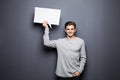 Young smile man holding white blank speech bubble with space for text isolated on grey background. Royalty Free Stock Photo