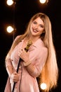 Young smiley beautiful long hair girl with microphone singing