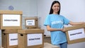 Young smiling activist holding donation box, volunteering center, philanthropy