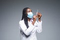 Young smiling African American doctor in medical mask holding a syringe isolated on gray Royalty Free Stock Photo