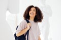 Young smiling african american female student in casual wear with backpack among plaster statues