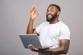 Young smiling african american man standing and using laptop computer isolated over grey background. Ok sign Royalty Free Stock Photo