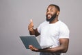 Young smiling african american man standing and using laptop computer isolated over grey background. Thumbs up sign Royalty Free Stock Photo