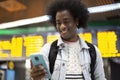 Young smiling African American man using his mobile phone at the airport Royalty Free Stock Photo