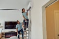 Truly professionals. Young smiling afro american woman in uniform cleaning the air conditioner while standing on the Royalty Free Stock Photo