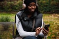 Young smiling afro woman using mobile phone while sitting in park Royalty Free Stock Photo