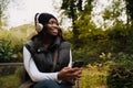 Young smiling afro woman using mobile phone while sitting in park Royalty Free Stock Photo