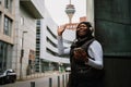 Young smiling afro woman using mobile phone and waving while standing outdoors Royalty Free Stock Photo