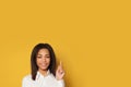 Young smiling American woman pointing up on yellow background with copy space Royalty Free Stock Photo