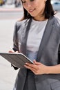 Young smiling Asian entrepreneur standing on city street using digital tablet. Royalty Free Stock Photo