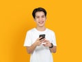 Young smiling Asian man with holding smart phone on orange background. copy space for put advertisement. Royalty Free Stock Photo
