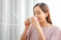 Young smiling Asian woman is relaxing with a cup of hot tea. Attractive girl is holding a white mug, Happy girl relaxing at home Royalty Free Stock Photo