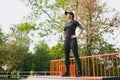 Young smiling athletic beautiful brunette girl in black uniform, cap with headphones doing sport exercises, warm-up Royalty Free Stock Photo