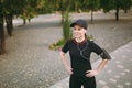 Young smiling athletic beautiful brunette girl in black uniform, cap with headphones doing sport exercises, warm-up Royalty Free Stock Photo