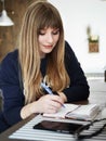 Young smiling attractive young woman with pen in hand thinking on plans and writing list to do in notepad enjoying Royalty Free Stock Photo