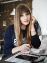 Young smiling attractive young woman with pen in hand thinking on plans and writing list to do in notepad enjoying Royalty Free Stock Photo