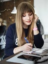Young smiling attractive young woman with pen in hand thinking on plans and writing list to do in notepad enjoying Royalty Free Stock Photo