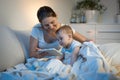 Young smiling with baby boy watching cartoons on digital tablet before going to sleep Royalty Free Stock Photo