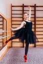 Young Smiling Ballerina Wearing black Tutu Doing exercise in training hall