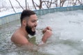 Young smiling bearded man in an ice hole in a frozen swimming pool on a winter day Royalty Free Stock Photo