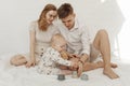 Young smiling beauteous family with cherubic infant baby playing with modern pastel silicone bowls of different size.