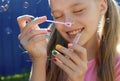 A young smiling beautiful blonde girl inflates soap bubbles in the summer Royalty Free Stock Photo