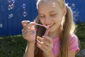 A young smiling beautiful blonde girl inflates soap bubbles in the summer Royalty Free Stock Photo