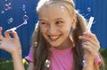 A young smiling beautiful blonde girl inflates soap bubbles in the summer Royalty Free Stock Photo