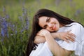 Young smiling beautiful brunette woman in white dress is sitting in green meadow with lupine flowers in spring Royalty Free Stock Photo