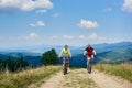 Young smiling bikers man and woman in professional sportswear riding bikes on dusty mountain road Royalty Free Stock Photo