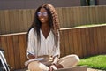 Young smiling black girl student studying sitting outdoors on sunny day. Royalty Free Stock Photo