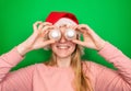 Young smiling blonde girl in a red winter Christmas Santa Claus hat holds Christmas decorative white balls in her hands near her Royalty Free Stock Photo