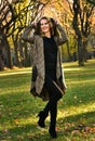 Young smiling blonde woman in elegant coat posing pretty in autumn park