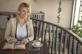 Young smiling blonde woman in a restaurant reading a book and drinking coffee Royalty Free Stock Photo