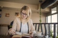 Young smiling blonde woman in a restaurant reading a book and drinking coffee Royalty Free Stock Photo