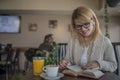 Young smiling blonde woman in a restaurant reading a book and dr Royalty Free Stock Photo