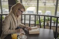 Young smiling woman in a restaurant reading a book and taking no Royalty Free Stock Photo