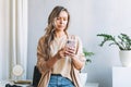 Young smiling blonde woman with long hair in stylish cardigan working at laptop in the bright modern office, woman send message by Royalty Free Stock Photo