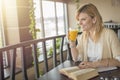 Young smiling blonde woman in a restaurant reading a book and dr Royalty Free Stock Photo