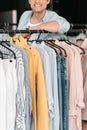 Young smiling boutique owner standing near clothes