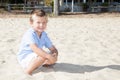 Smiling boy sit on sand beach during vaction day