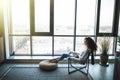 Young smiling brunette girl is sitting on modern chair near the window in light cozy room at home working on laptop in relaxing Royalty Free Stock Photo