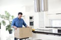 Young smiling brunette man unpacking box with kitchen tools at home Royalty Free Stock Photo