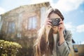 Young smiling brunette taking picture with photo camera outdoors Royalty Free Stock Photo