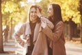 Young smiling brunette twin girls having fun with hands close to the head in one of them, in casual coat standing close Royalty Free Stock Photo