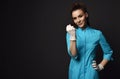 Young smiling brunette woman doctor nurse in blue medical gown and latex gloves shakes her fist at us at copy space Royalty Free Stock Photo